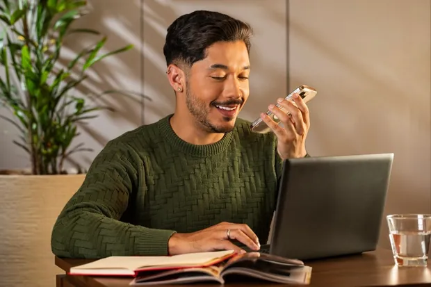Homem usando notebook enquanto come um chocolate